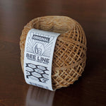 Ball of brown hemp wick with a label on a wooden surface