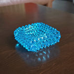 Blue hobnail glass dish on a wooden surface