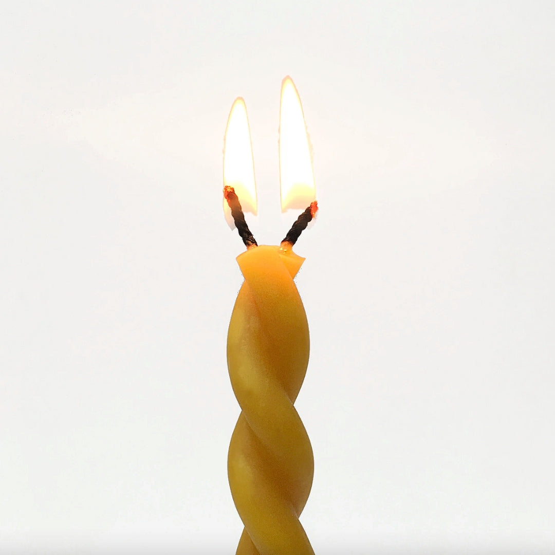Twisted yellow candle on a white background