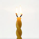 Twisted yellow candle on a white background