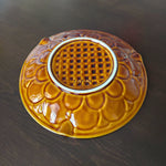 bottom of brown ceramic dish with intricate design on a dark surface