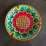 Decorative ceramic dish with a colorful floral pattern on a dark surface