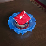 Blue sea glass dish with a red jewelry pouch and jewelry on a wooden surface