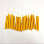 Row of beeswax candles with cotton wicks on a white background