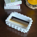 White decorative box with a gold and black object on a wooden surface